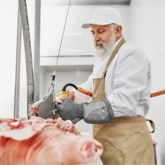 butcher in gloves cutting pork carcasses with elec 2023 11 27 05 23 16 utc 2